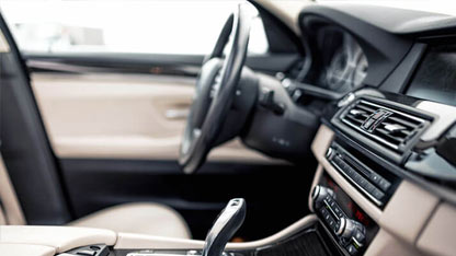 Interior de un automóvil moderno, centrándose en el volante, tablero de instrumentos y palanca de cambios.